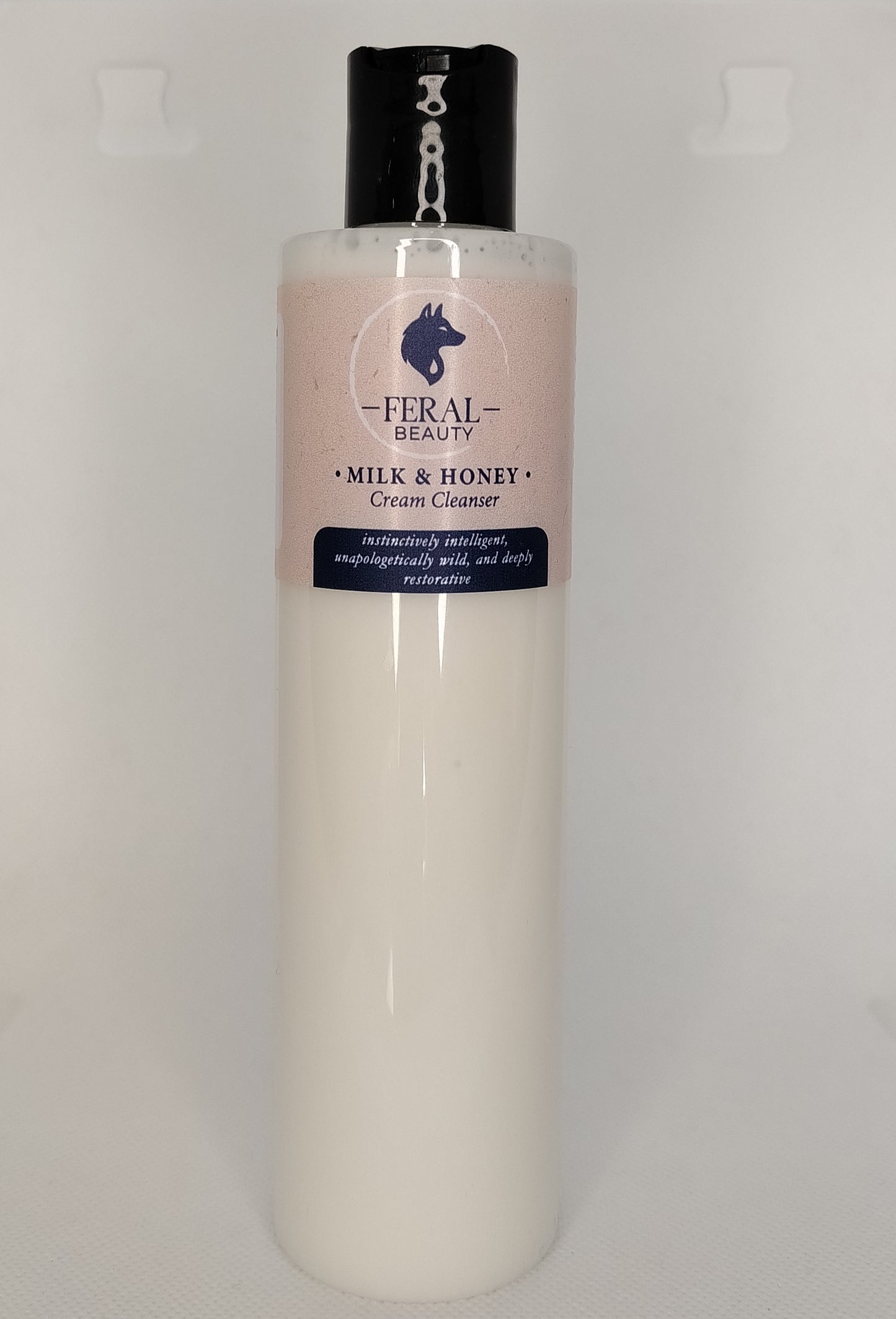Bottle of Feral Beauty Milk & Honey Cream Cleanser on a light gray background