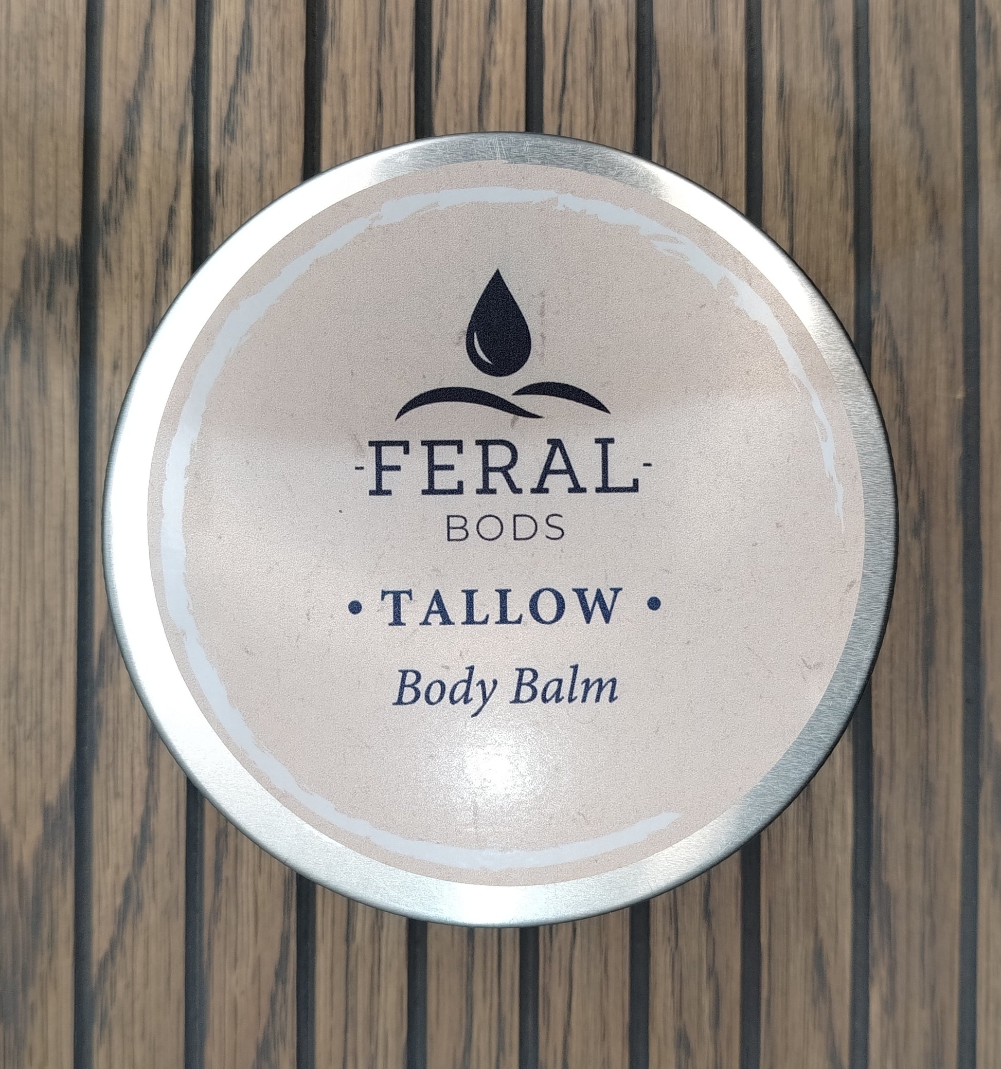 Feral Bods Tallow Body Balm container on a wooden surface